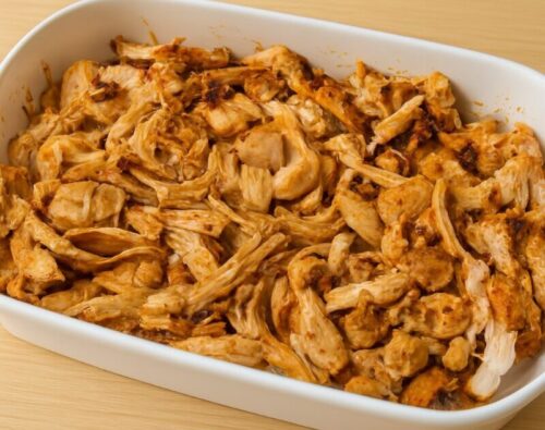 Cooked chicken being shredded with a fork into small pieces for homemade chicken taco filling