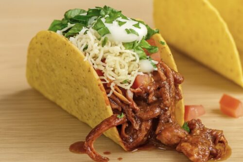 Crispy taco shells filled with shredded chicken, lettuce, tomato, cheese, and sour cream for homemade chicken tacos