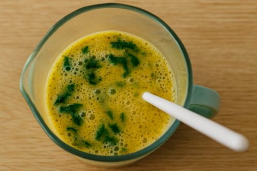 Whisked eggs mixed with cooked spinach and crumbled feta cheese in a large bowl