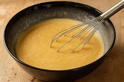 Mixing mashed bananas, eggs, oat milk, and honey in a large bowl for healthy banana bread batter.