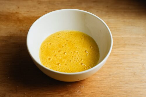 Cracked eggs in a bowl with salt and pepper, whisked until light and fluffy.