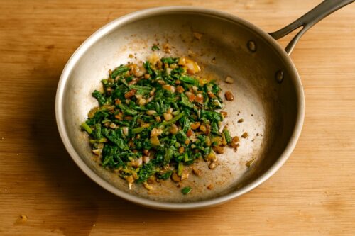 Chopped onions, mushrooms, and spinach sautéing in olive oil until soft and cooked.
