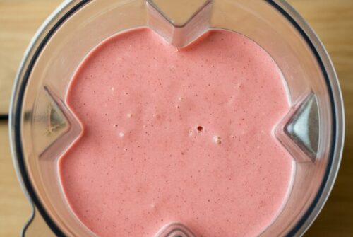Blending smoothie ingredients until creamy and smooth texture is achieved.