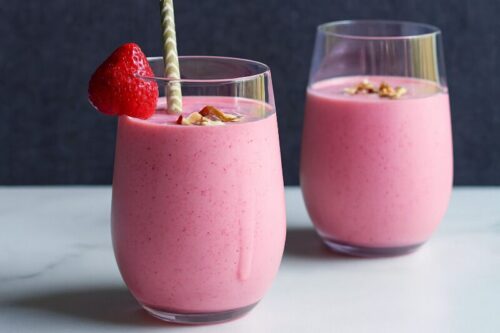 Serving strawberry banana smoothie in a glass topped with oats and almond slices for a fresh, chilled finish.