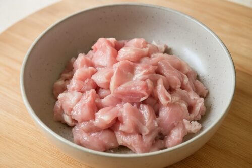 Raw chicken thighs or breast cut into medium-sized pieces for cooking prep