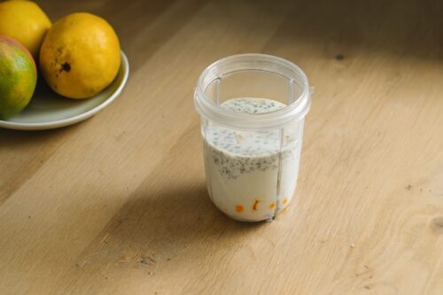 Step-by-step process of making mango chia seed smoothie: soaking chia seeds, adding chopped mango, curd, milk, sugar, and soaked chia seeds into blender before blending