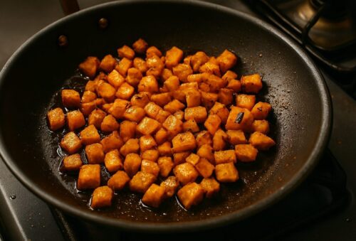 Sweet potato cubes tossed with olive oil, smoked paprika, salt, and pepper in mixing bowl