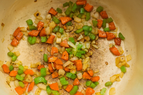 Carrots, celery and onions being sautéed in a pot