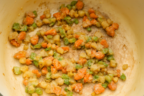 Sprinkling flour over sautéed vegetables to thicken the soup.
